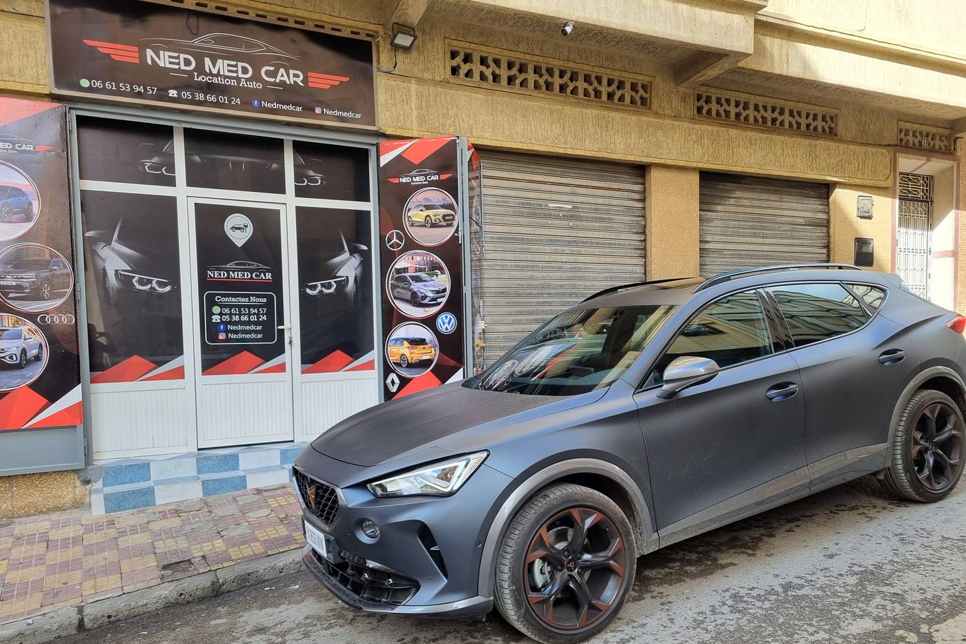 L'enseigne Ned Med Car Location Auto et notre CUPRA gris mat garé devant l'agence, à Tanger